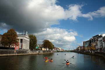 Kajakarze płynący rzeką przez miasto Cork. Irlandia. - obrazy, fototapety, plakaty