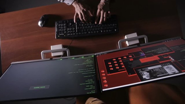 Hacker at night typing on a computer keyboard hacking secret information. HD.
