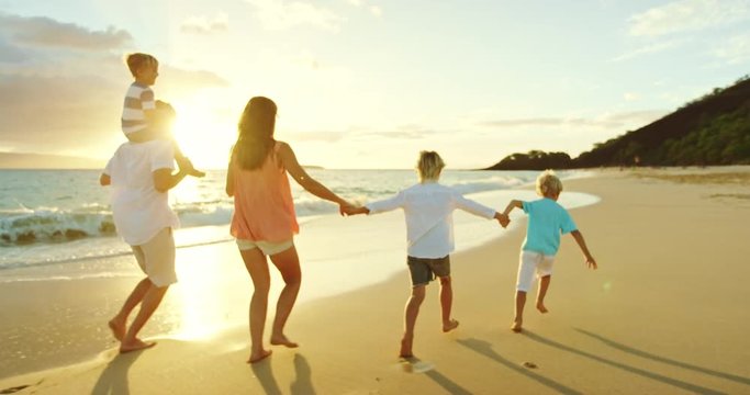 Happy family walking down the beach at sunset