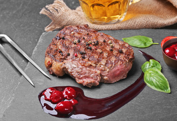 Tasty juicy steak with spices and sauce on slate plate