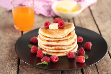 Plate full of tasty pancakes with raspberries