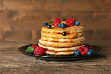 Black plate full of yummy pancakes with berries