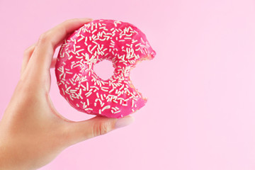 Female hand holding delicious donut on pink background, closeup - Powered by Adobe