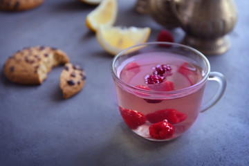 Cup of fresh berry tea with biscuit on table