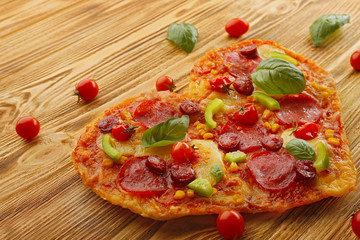 Tasty heart shaped pizza on wooden background