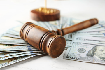 Judge's gavel and dollar banknotes on white table