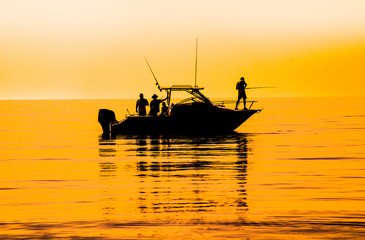 silhouette of sport fishing boat reflecting on calm water - 125861391