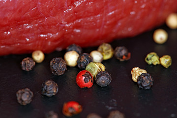 Pepper and raw meat steak on black background. Fresh, raw, organic vegetables. Cooking, Healthy eating concept.