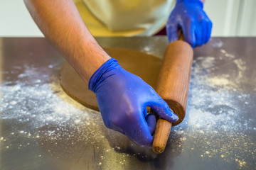 hand rolled out dough with gloves on the table. Preparing cakes