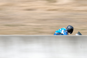 Motorcycle racer passes between wall and hillside