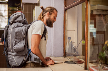 Male tourist buys a ticket at terminal station ticket counter