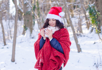 Fototapeta na wymiar Portrait of a beautiful smiling girl in santa hat in winter forest