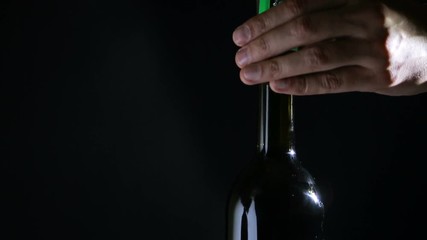 hand man using corkscrew to open a bottle of wine. Black background