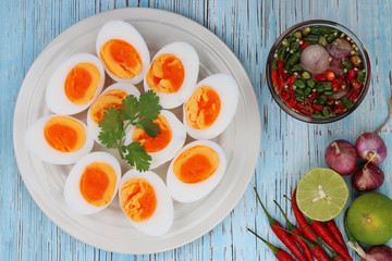 Boiled eggs and fish sauce with chilli lemon and shallots on blue wood floor. Thai food