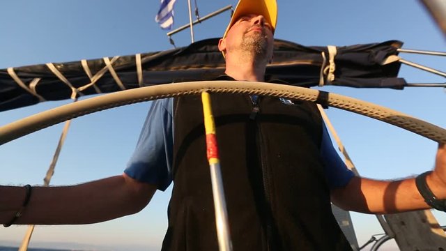 Sailor skipper steers sailing vessel in the open sea.