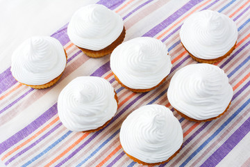 White cupcakes on the striped linen napkin top view