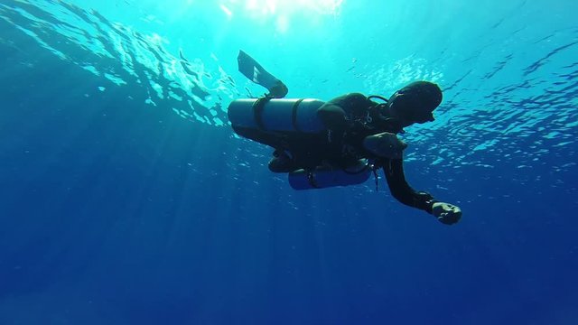 Technical diver with sidemouth set makes ok sign and diving in clear blue water, Maldives, Indian Ocean. Scuba diver enjoy mounting cylinders on their sides.