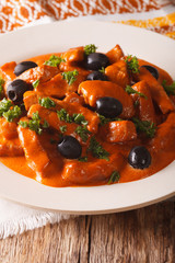 Spanish pork Raxo in a spicy sauce of wine, tomatoes and cream close-up on a plate. vertical