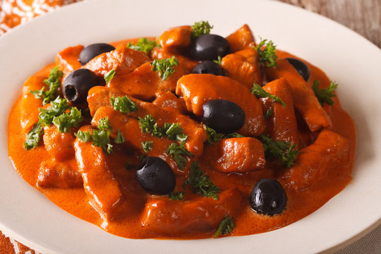 Spanish Food: pork Raxo in spicy sauce with olives close-up. horizontal