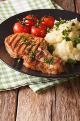 Grilled pork loin with mashed potatoes and tomato close-up. Vertical, rustic
