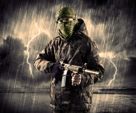 Dangerous armed terrorist with mask and gun in a thunderstorm wi