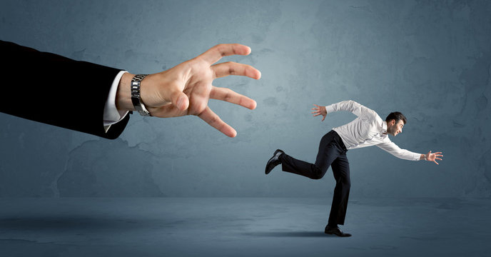Business man running away from a huge hand concept
