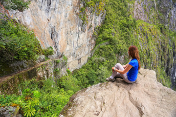 Naklejka na ściany i meble Young woman enjoying the view of Inca Bridge and cliff path near