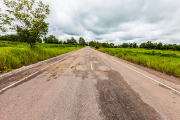 Damaged asphalt pavement road with potholes