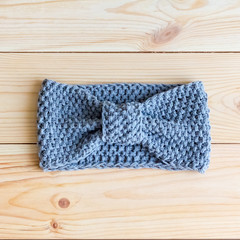 Headband gray-blue color knit hand on wooden backgroundHeadband gray-blue color knit hand on wooden background