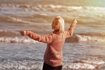 White-haired girl walking along the beach at sunset. Girl fooling around at sea. The feeling of...