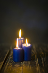 Obraz na płótnie Canvas Lit three blue candles on wooden counter