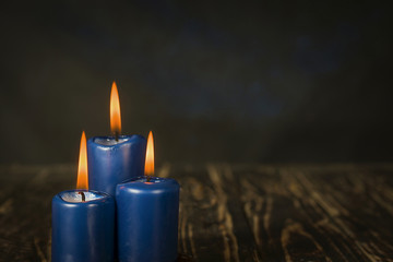 Lit three blue candles on wooden counter