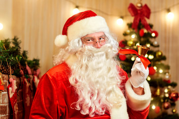 Closeup of Santa Claus with a gold bell in the hands indoors at