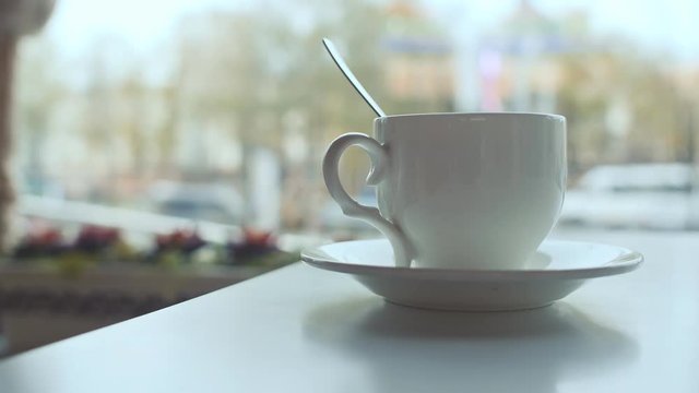 White coffee cup on the table in coffee against a background window
