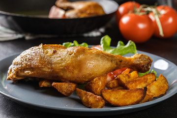 Roasted chicken legs with potato wedges and tomatoes