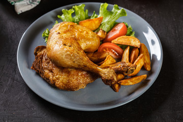 Roasted chicken legs with potato wedges and tomatoes