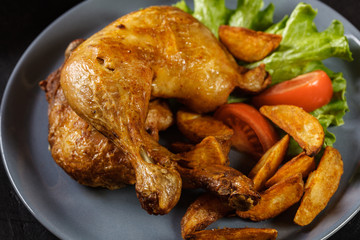 Roasted chicken legs with potato wedges and tomatoes