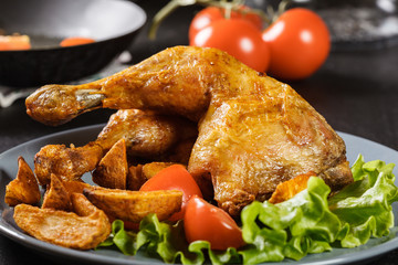 Roasted chicken legs with potato wedges and tomatoes