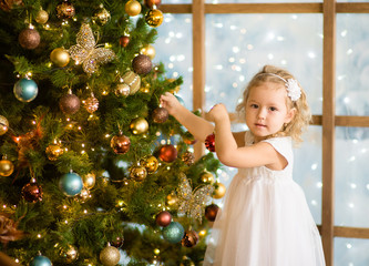 Little girl decorates the Christmas tree