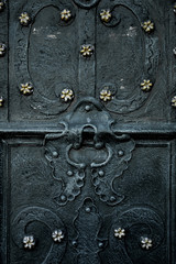 Vintage black door decorated with metal flower. Close up.