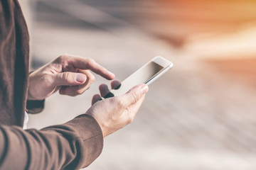 Man's hands using mobile smartphone outdoors