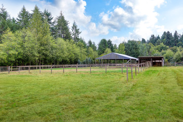 Fototapeta na wymiar Farm field with empty horse barn