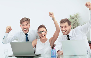 Team of three work colleagues with their arms raised in celebrat