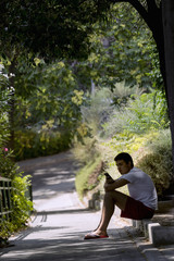 Fototapeta premium Teenager, sitting on a curb, using the mobile phone