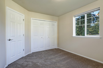 White doors closet and a window in empty beige room