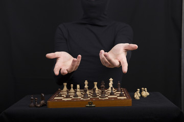 girl in a black blouse holds hands on a wooden chess board with