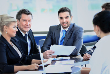 Smiling young man sitting at a business meeting with colleagues