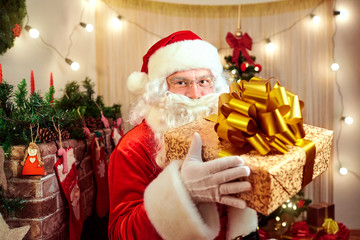 Santa Claus with a gift with a large gold bow in the hands in th