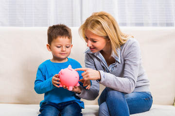 Happy mother and son are holding piggy bank.