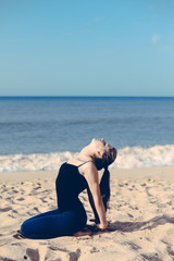 Woman on the beach doing fitness yoga, sunny blue sky ocean background outdoors